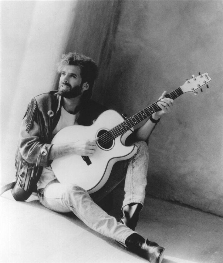 a man sitting on the floor playing a guitar