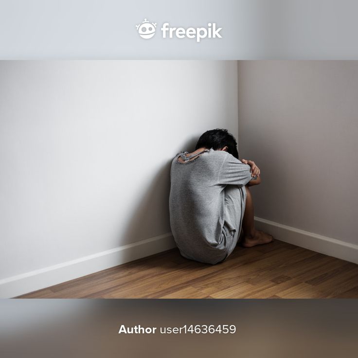 a person sitting on the floor in front of a wall with their head under his hands