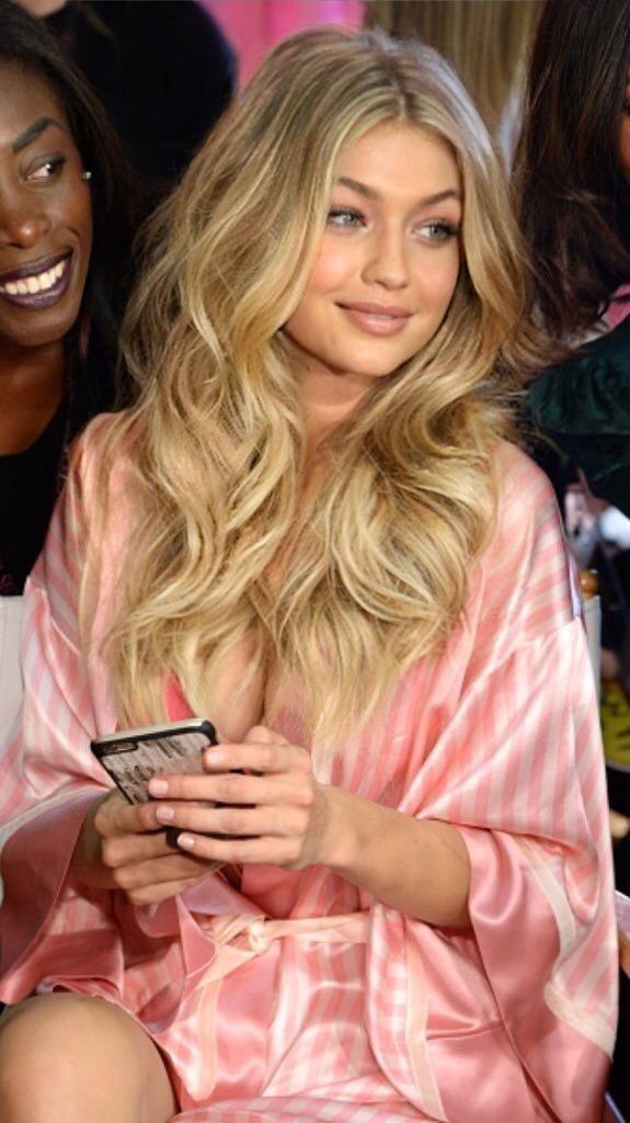 a woman sitting next to another woman in a pink robe and holding a cell phone