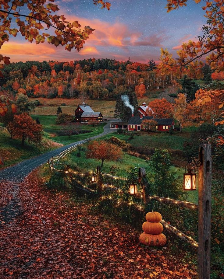 an autumn scene with pumpkins on the ground and houses in the background at sunset