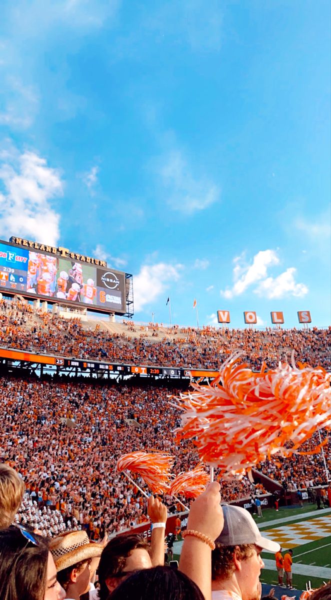 fans at a football game are holding up orange streamers in the air as they cheer for their team