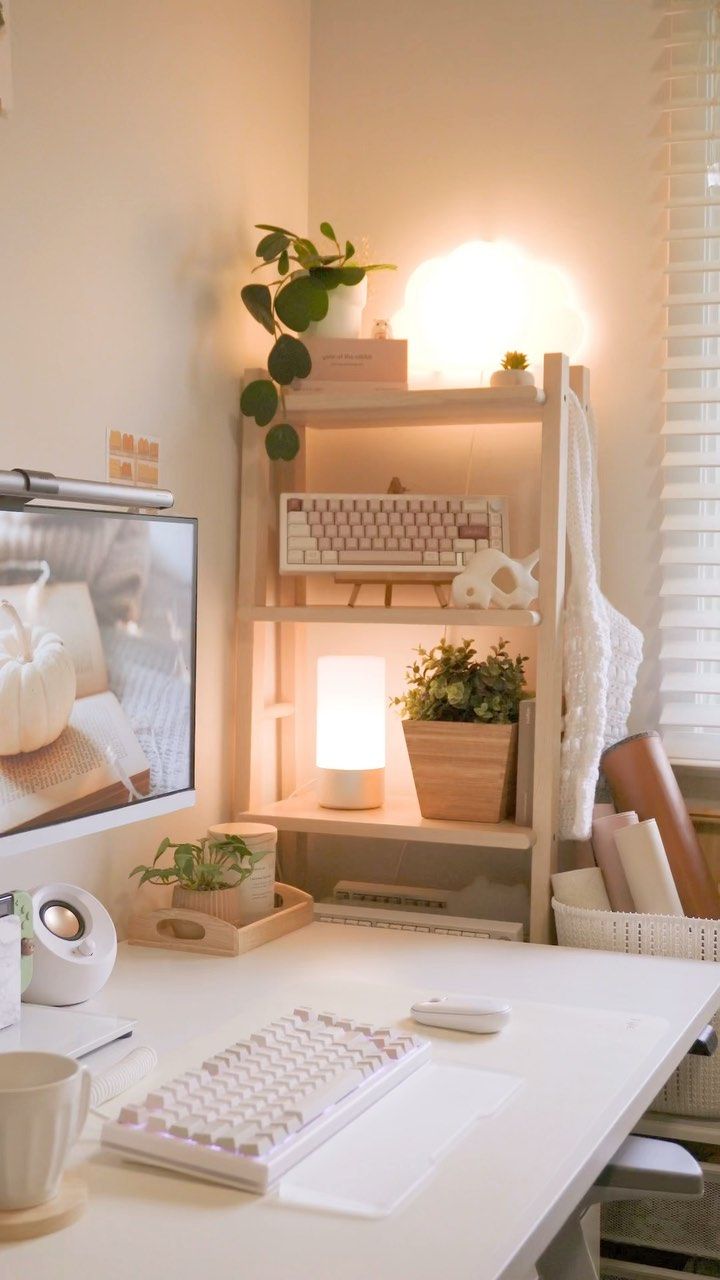 a white desk with a computer monitor and keyboard on it next to a potted plant