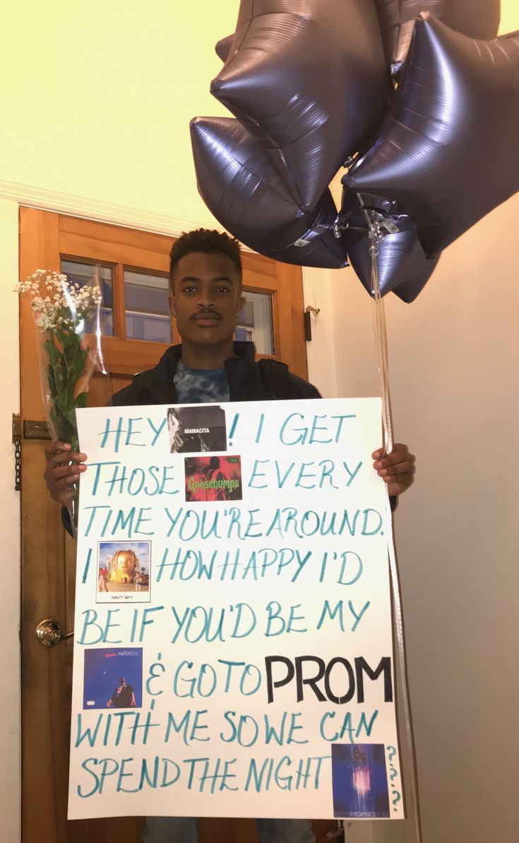 a man holding up a sign with balloons