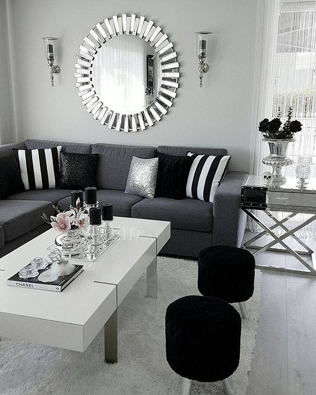 a living room filled with black and white furniture next to a large mirror on the wall