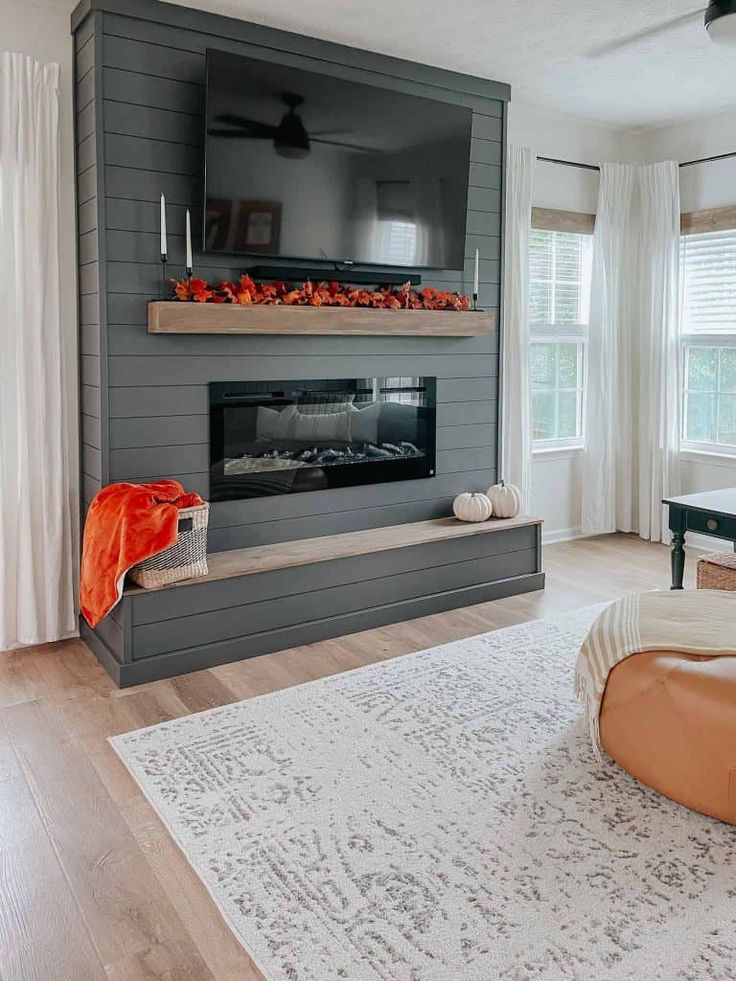 a living room filled with furniture and a flat screen tv mounted on the wall above a fire place