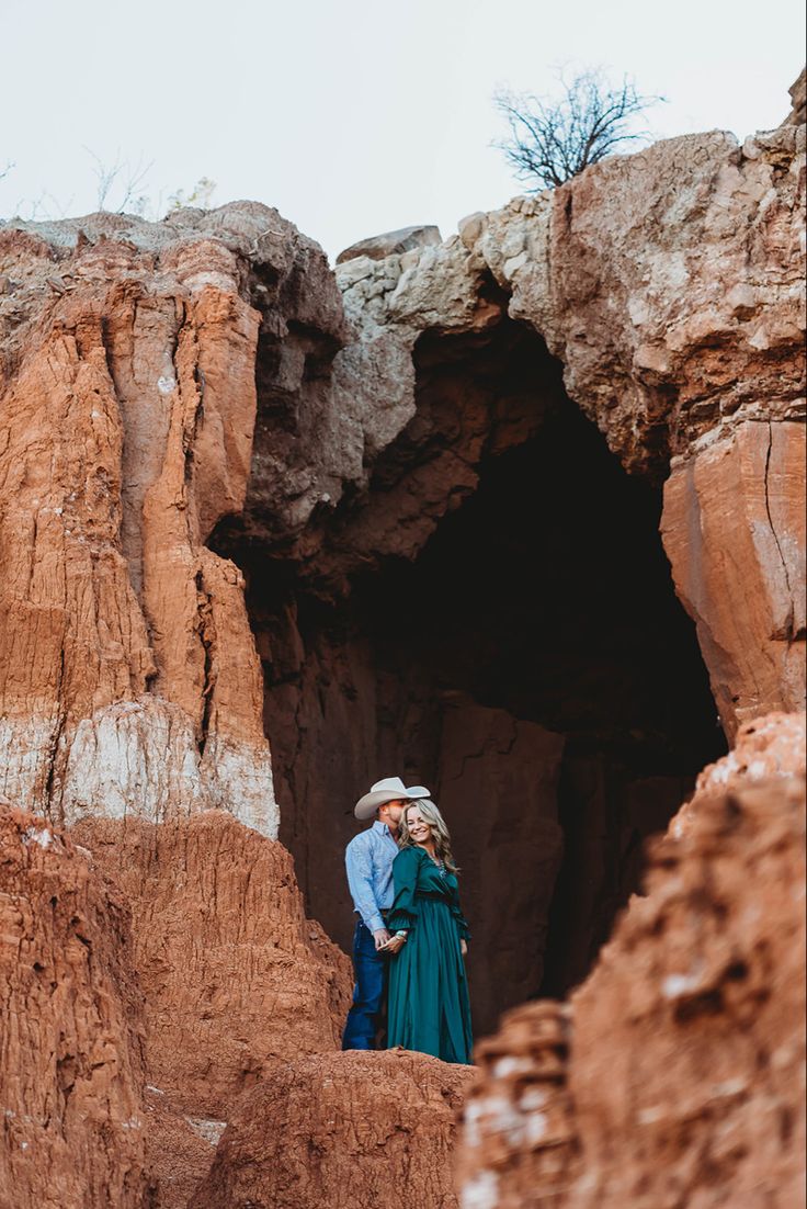 an engaged couple standing in the middle of a rocky area with their arms around each other