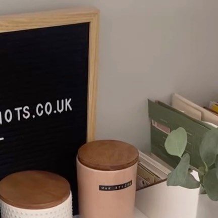 two trash cans sitting next to each other on a shelf in front of a chalkboard