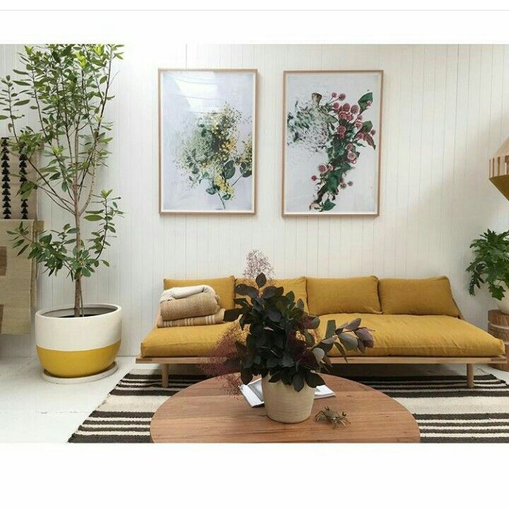 a living room with yellow couches and potted plants on the coffee table in front of it