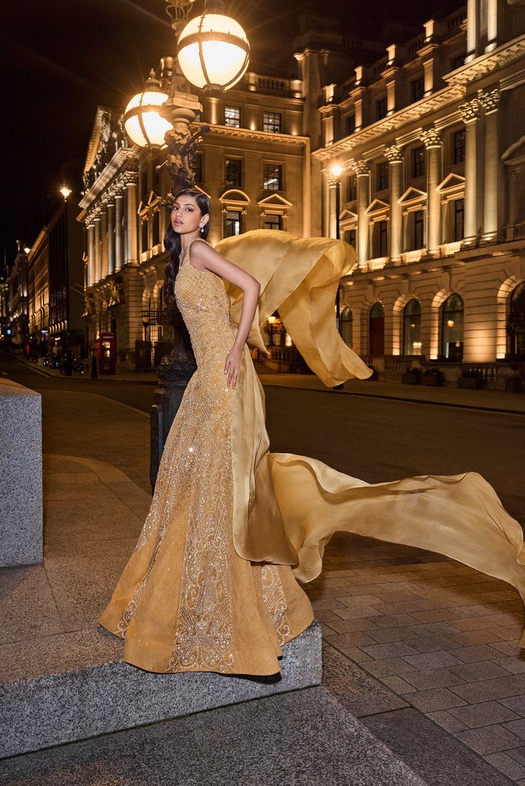 This golden gown set features embroidery in delicate gold coloured pearls in an abstract pattern. The plunging neckline of the gown has intricate cut work. The shapely gown also shows panels with heavy shrinkingly. An exaggerated satin organza bow has been used for styling purposes.From Seema Gujral's For the love of London collection. DELIVERY TIMEPlease allow 8-12 weeks for your outfit to arrive. FABRIC DETAILSNet Professional cleaning only. Party Gown With Detachable Train In Organza, Glamorous Silk Evening Dress With Sweep Train, Organza Party Gown With Detachable Train, Formal Gown With Sheer Bodice And Long Train, Luxury Evening Gown With Long Train, Organza Gown With Fitted Bodice For Gala, Luxury Floor-length Gown With Sheer Bodice, Luxury Silk Gown For Gala, Organza Evening Dress With Detachable Train For Gala