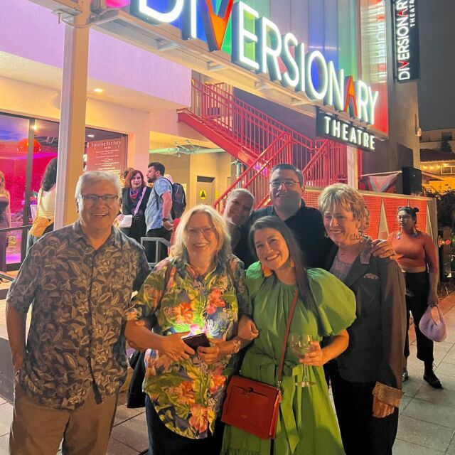 a group of people standing in front of a building with neon signs on the side