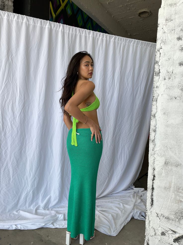 a woman standing in front of a white backdrop wearing a green skirt and matching top