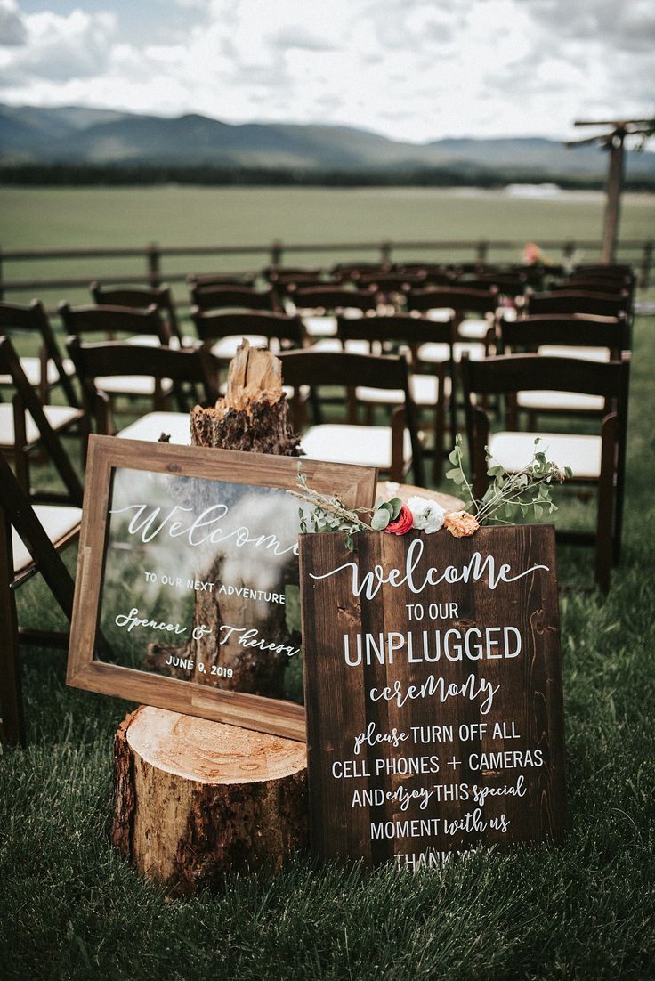 an outdoor ceremony with wooden chairs and signs