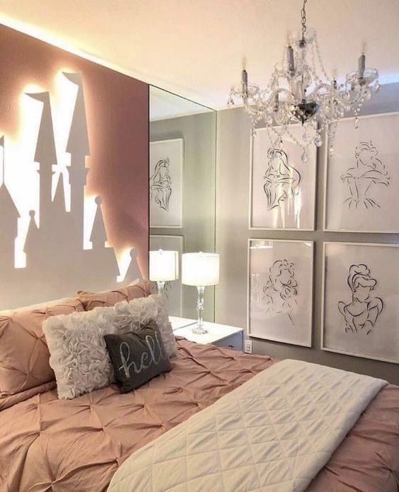 a bedroom with a bed, chandelier and pictures on the wall above it