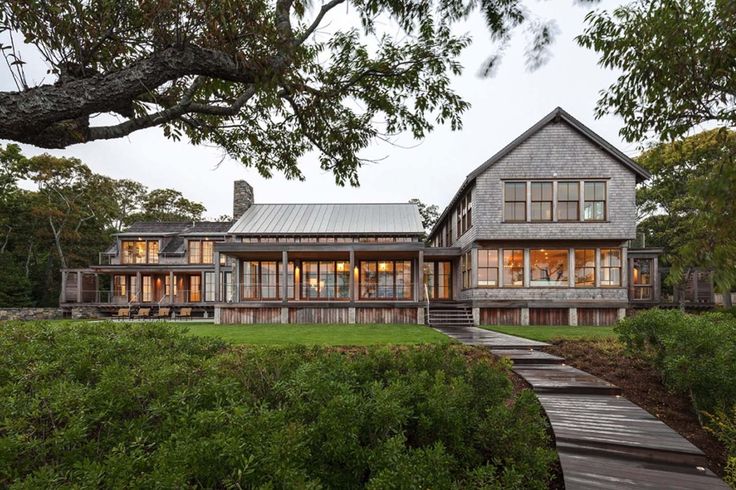 a large house sitting on top of a lush green field next to a wooden walkway