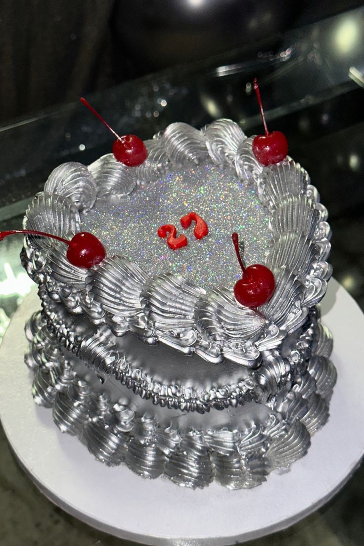 a silver cake with cherries on top