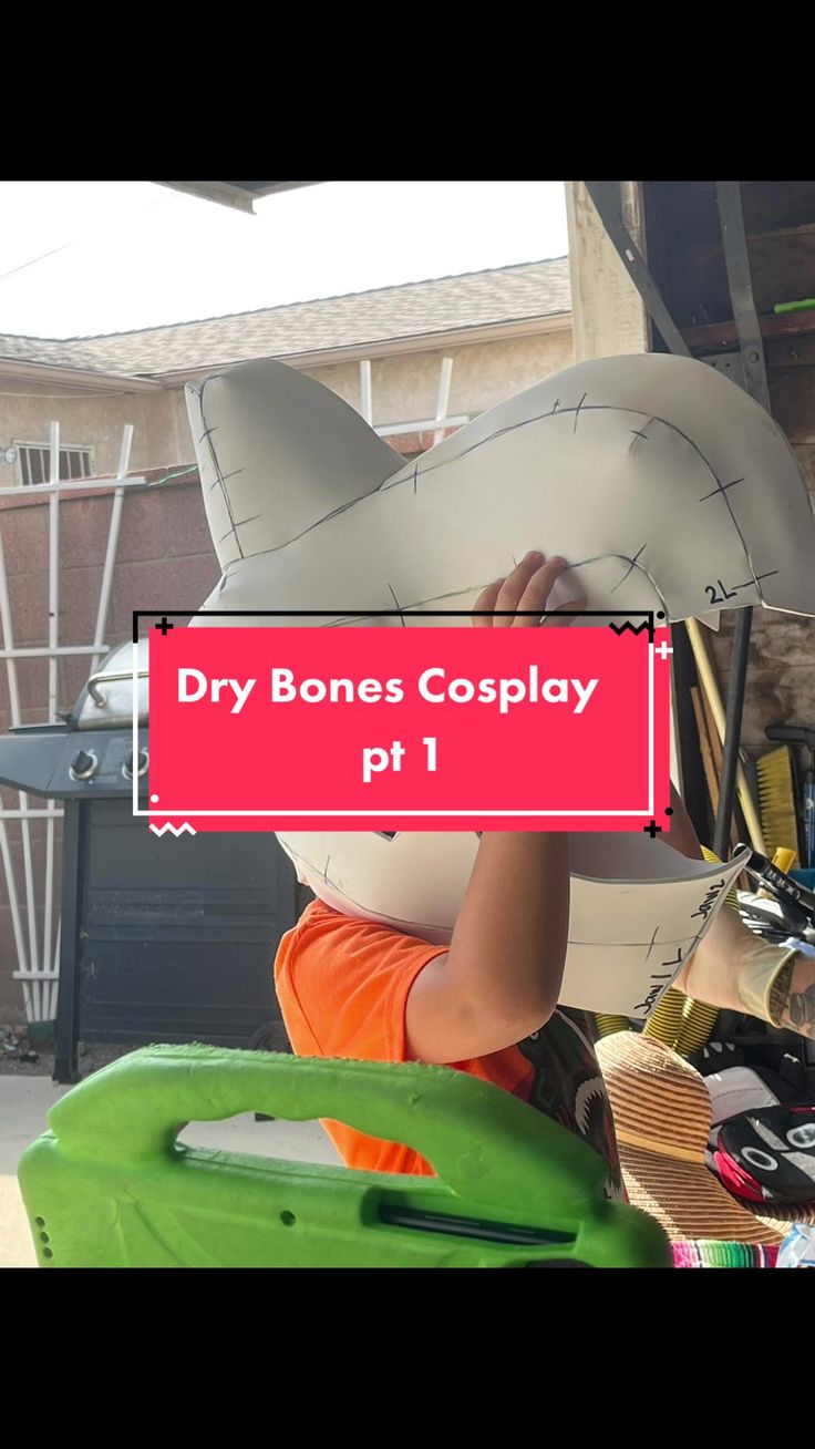 a boy is holding up a paper cut out of a shark with the words dry bones cosplay on it