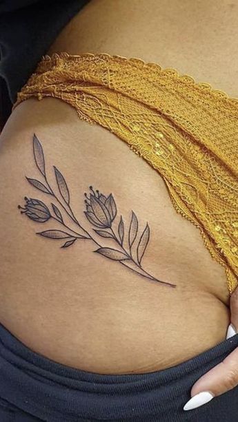 a woman's stomach with a flower tattoo on the side of her belly,