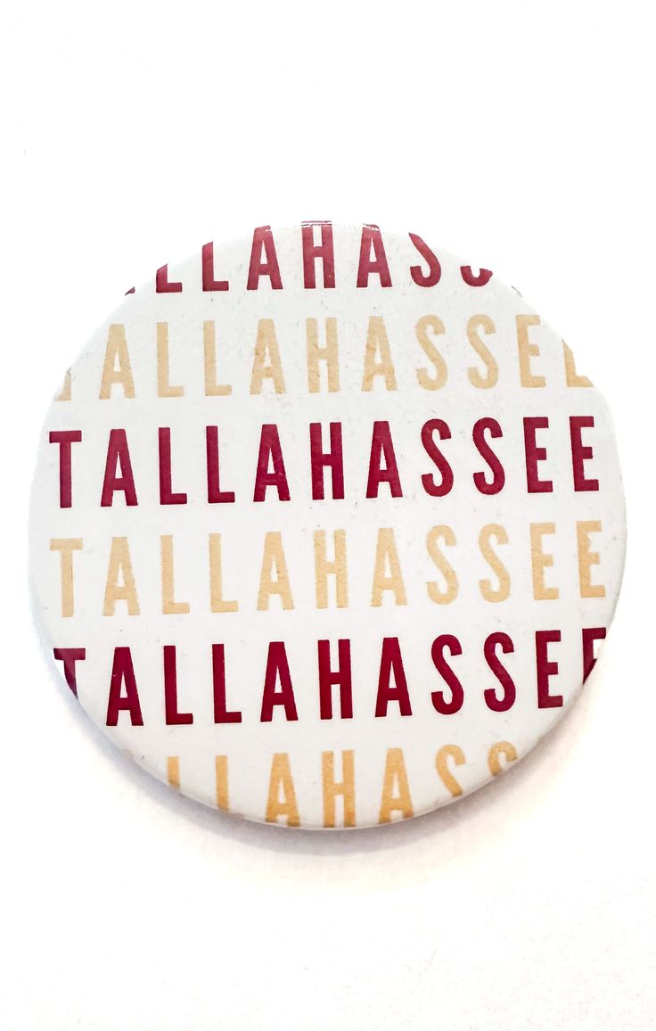 a button with words written on it in red and yellow colors, sitting on a white surface