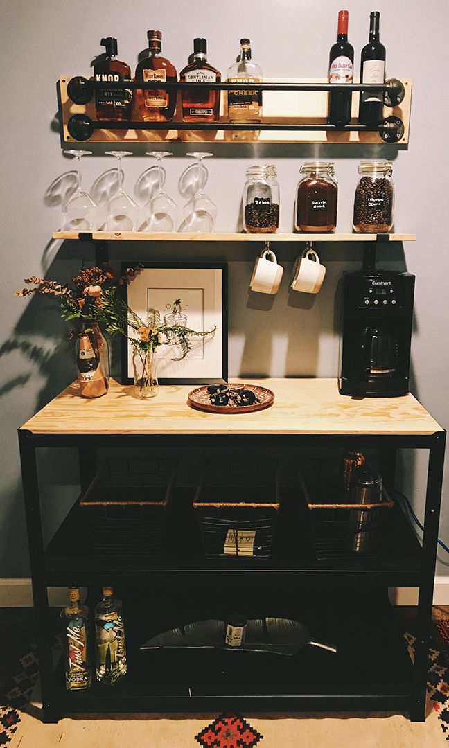 a shelf filled with bottles and glasses on top of a table next to a wall