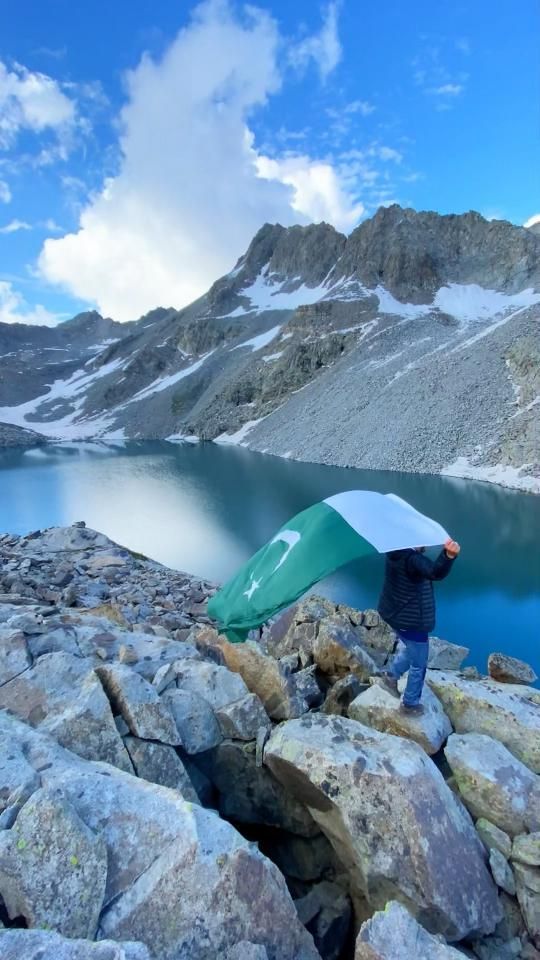 a man holding an umbrella on top of a rocky hill next to a body of water