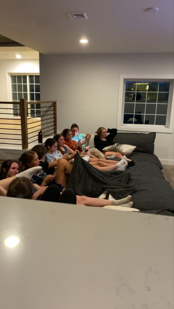 a group of people sitting on top of a couch in a living room next to each other