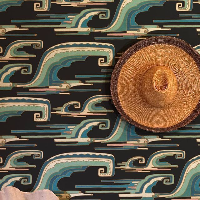 a straw hat sitting on top of a blue and green wallpapered floor next to a white towel