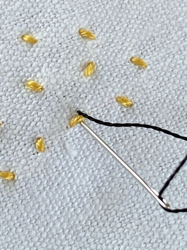 the needle has been hooked up to some tiny yellow seed beads that are sprinkled with thread