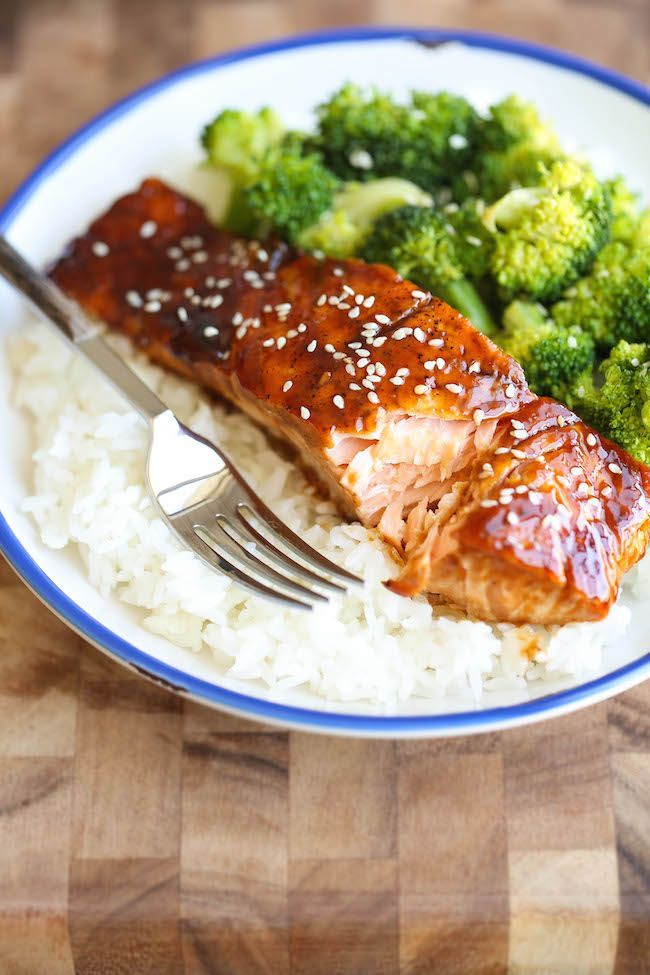 a plate with rice, broccoli and salmon on it next to a fork