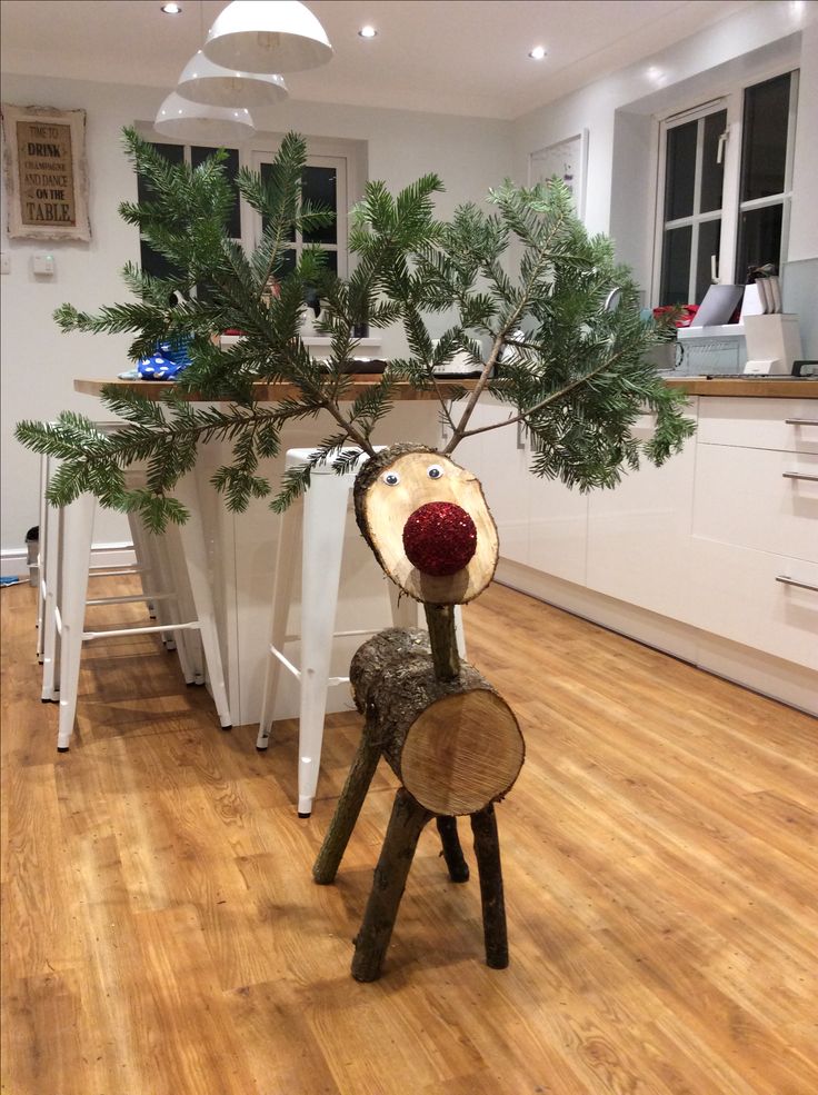 a reindeer made out of wood sitting on top of a hard wood floor in a kitchen