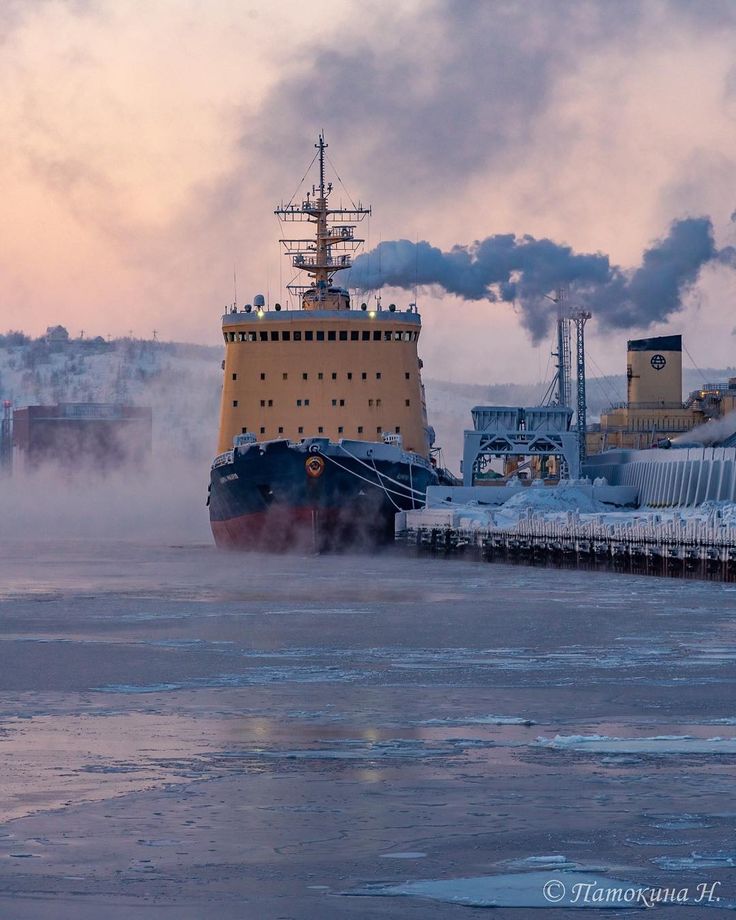 a large boat floating on top of a body of water next to snow covered ground