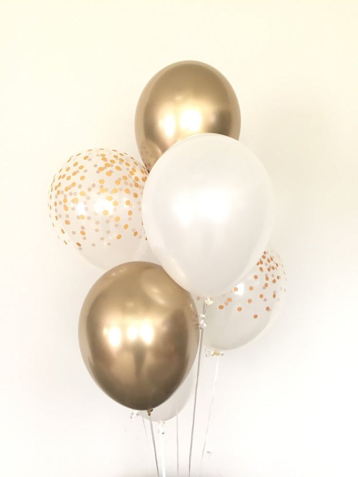 gold and white balloons in a vase on a table