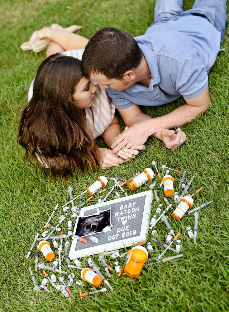 a man and woman laying on the grass next to an assortment of small orange objects