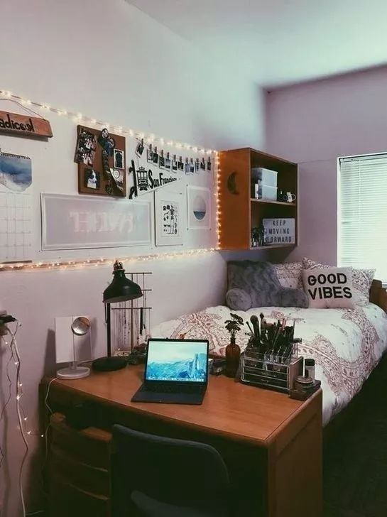 a desk with a laptop computer on top of it next to a bed covered in lights