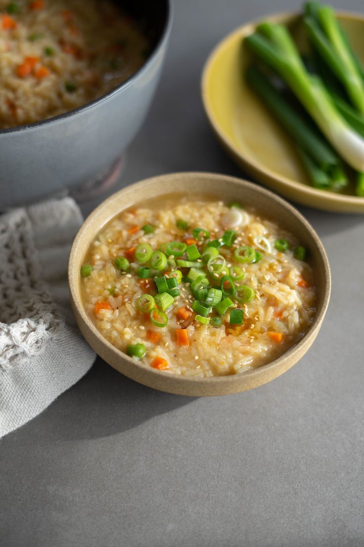 there is a bowl of rice and asparagus on the table next to it