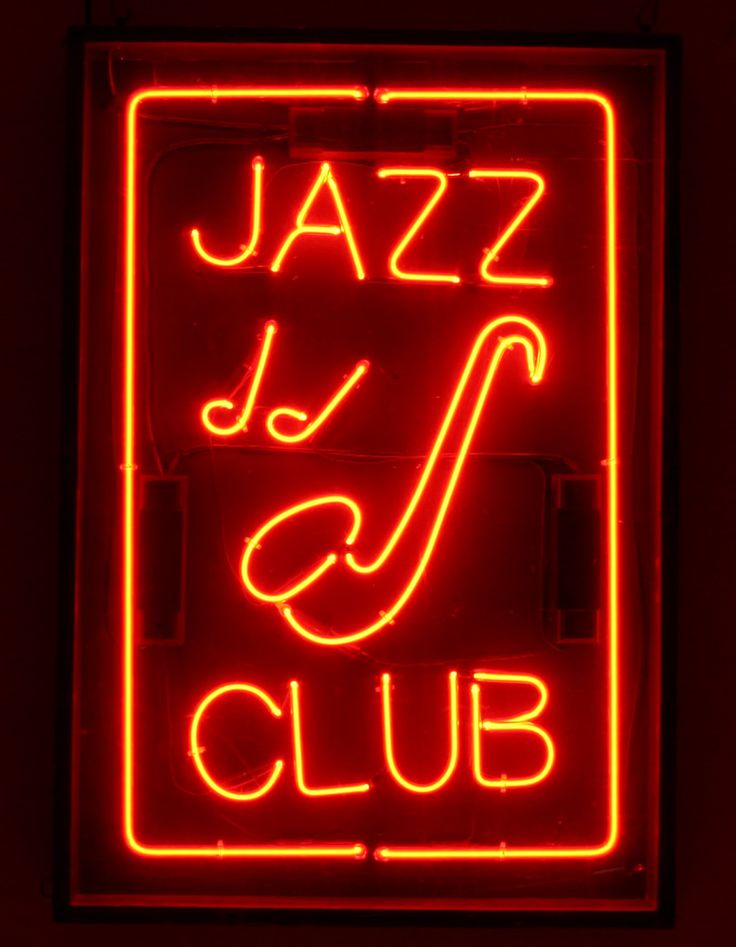 a red neon sign with the word jazz club written in white on it's side