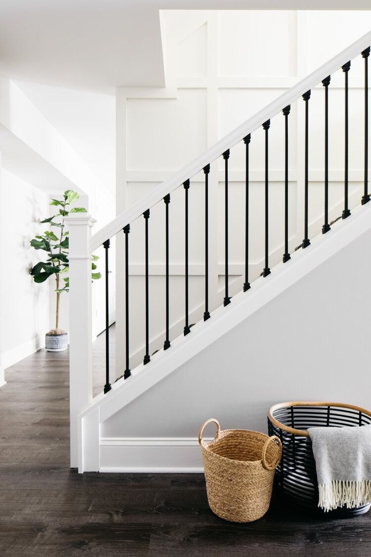 two baskets sitting on the floor next to a stair case and banister in a house