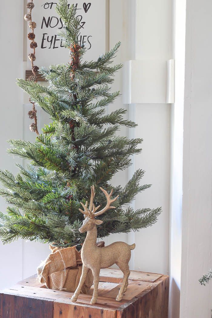 a small christmas tree sitting on top of a wooden box next to a deer figurine