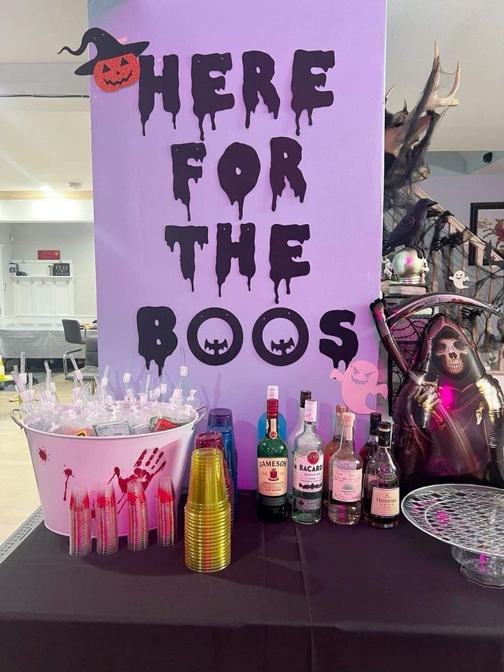 there is a purple sign that says here for the boos on it and some liquor bottles