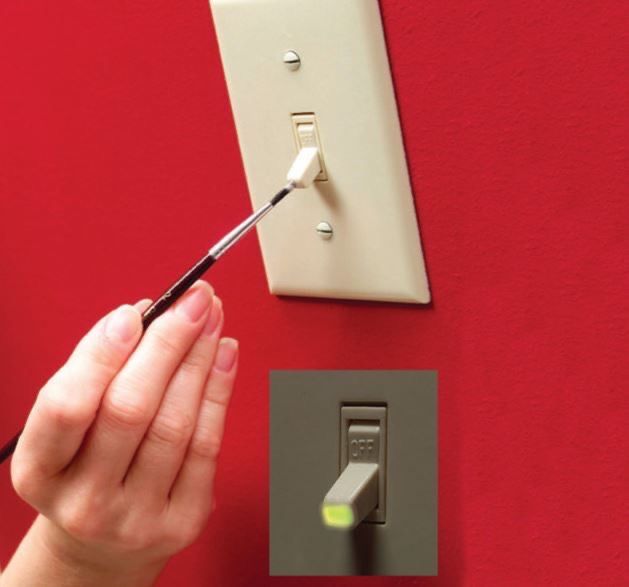 a person using a screwdriver to fix a light switch on a red wall