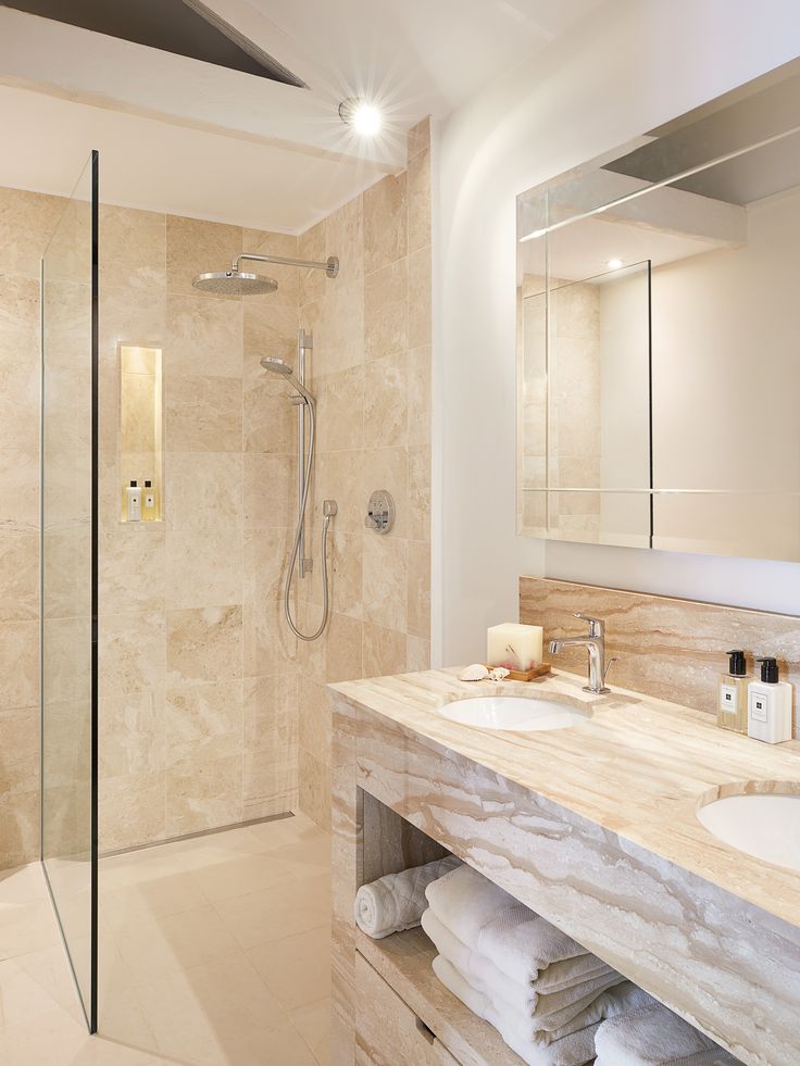 a bathroom with marble counter tops and a glass enclosed shower stall next to the sink