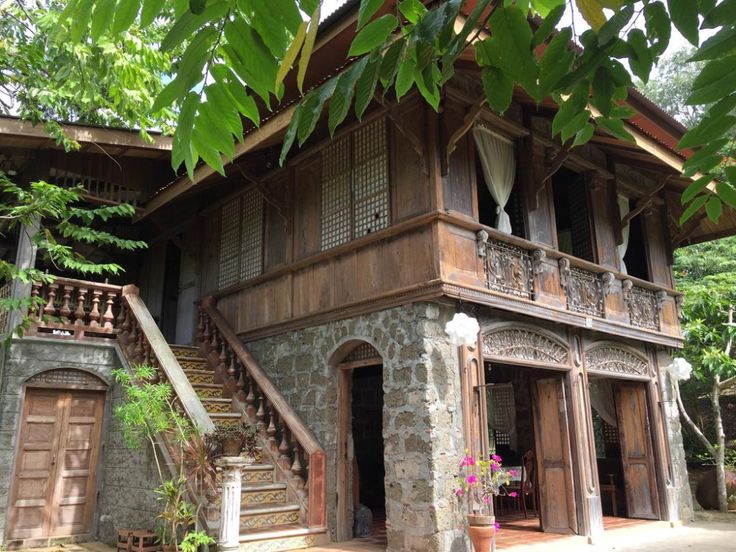 an old building with stone steps and wooden railings in front of it, surrounded by greenery