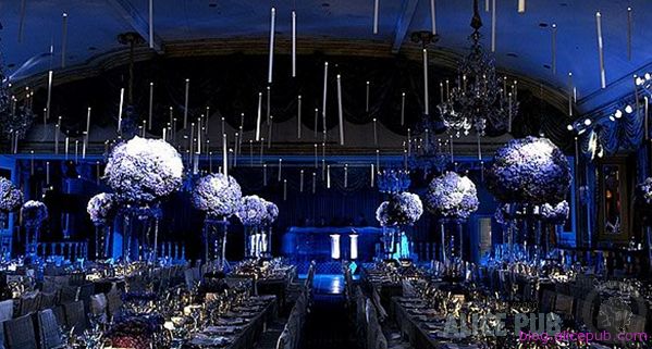 a large banquet hall with blue lighting and tall centerpieces