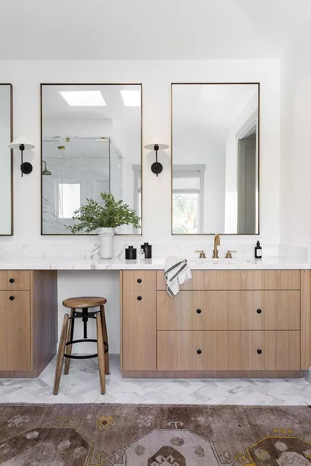 a bathroom with two sinks, mirrors and stools on the floor in front of it