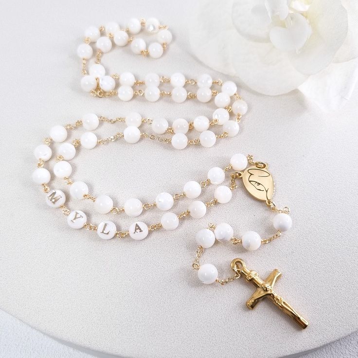 This Personalized Rosary, is ideal as a Baptism gift for a little girl or baby boy or as a gift for a special occasion. It is expertly handcrafted in a traditional style with a contemporary twist utilizing genuine Mother of pearl stone and gold-plated brass wire, which not only gives a touch of nature but also tenderness. The letter beads on the Rosary are also handmade from genuine mother of pearl, and the length is perfect to worn as a dainty Rosary necklace for women. *MATCHING ROSARY BRACELE Customized White Jewelry For Personalized Gifts, Handmade White Jewelry For Personalized Gift, Customized White Wedding Necklaces, Customized White Wedding Necklace, White Spiritual Cross Jewelry And Charms, Customizable White Necklaces For Personalized Gift, Customizable Cross Jewelry For Baptism, Pearl White Rosary With 8mm Beads As Gift, Customizable White Jewelry Gift