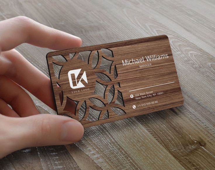 a hand holding a business card on top of a wooden table with woodgrain