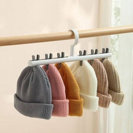 four hats hanging on a rack in front of a window