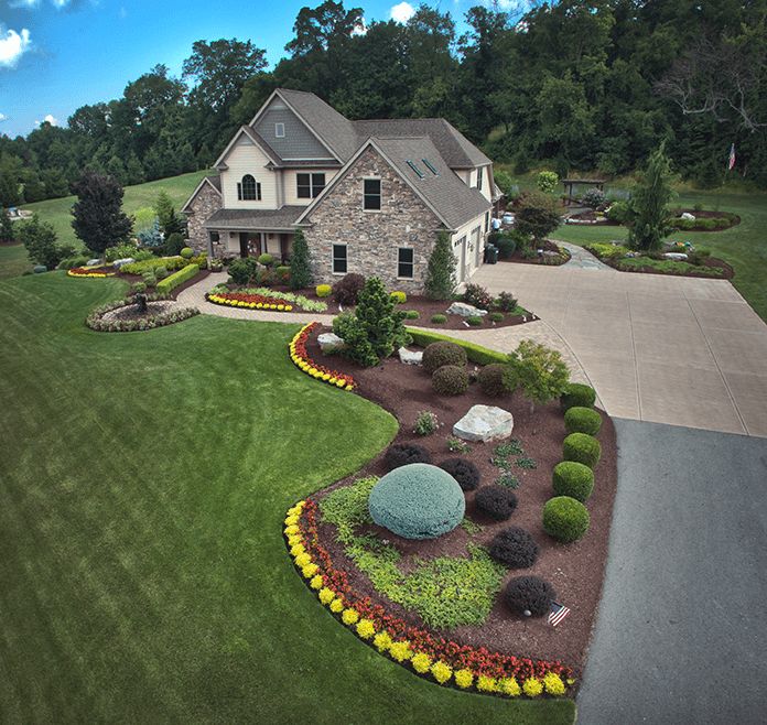 an aerial view of a large house with landscaping in the front yard and driveway area