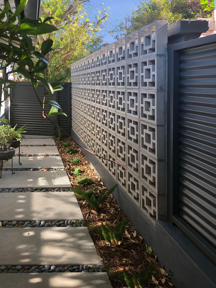 an outdoor walkway with stone steps leading up to the side of a house, surrounded by greenery and trees