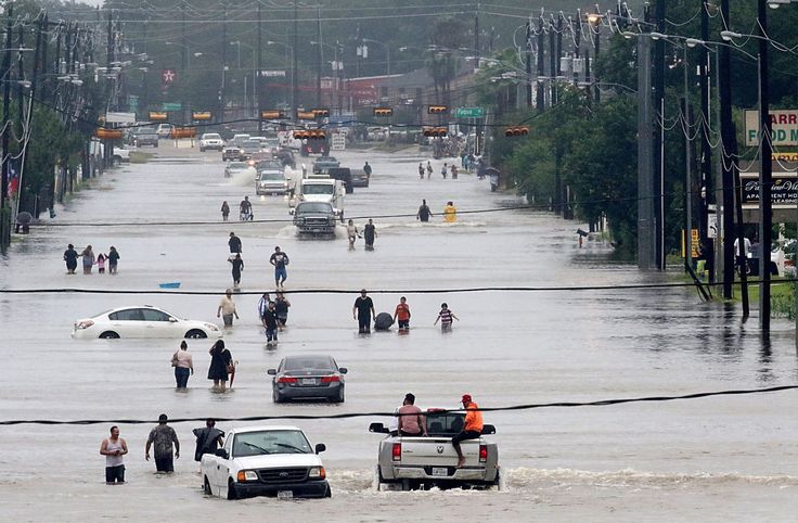 many people are walking through the flooded street