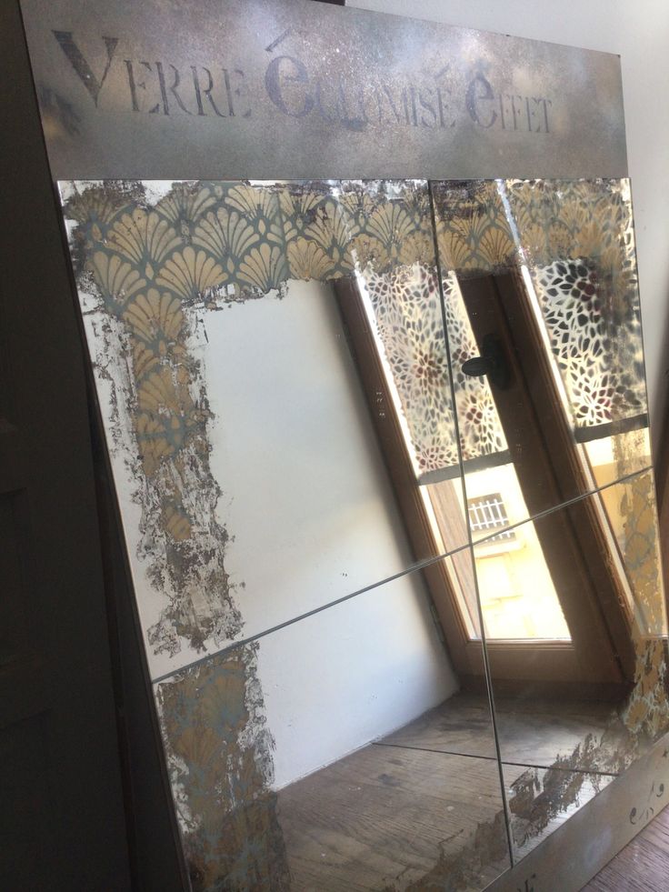 the reflection of two windows in a mirrored wall with gold and silver designs on it